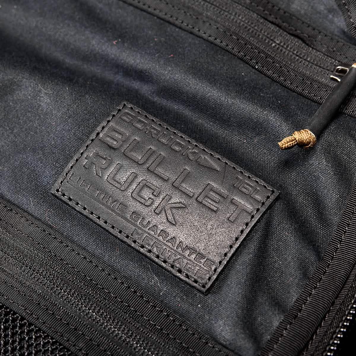 Close-up of black GORUCK Bullet Ruck backpack label embossed with lifetime guarantee on rugged fabric