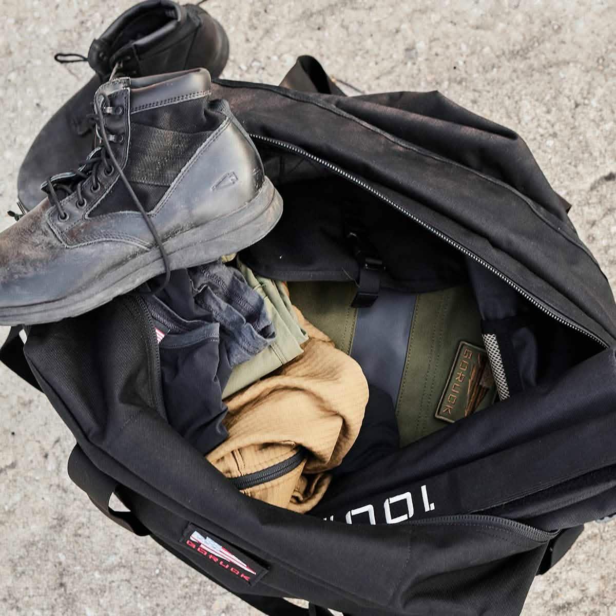 GORUCK black duffle bag with boots and rucking gear on concrete surface