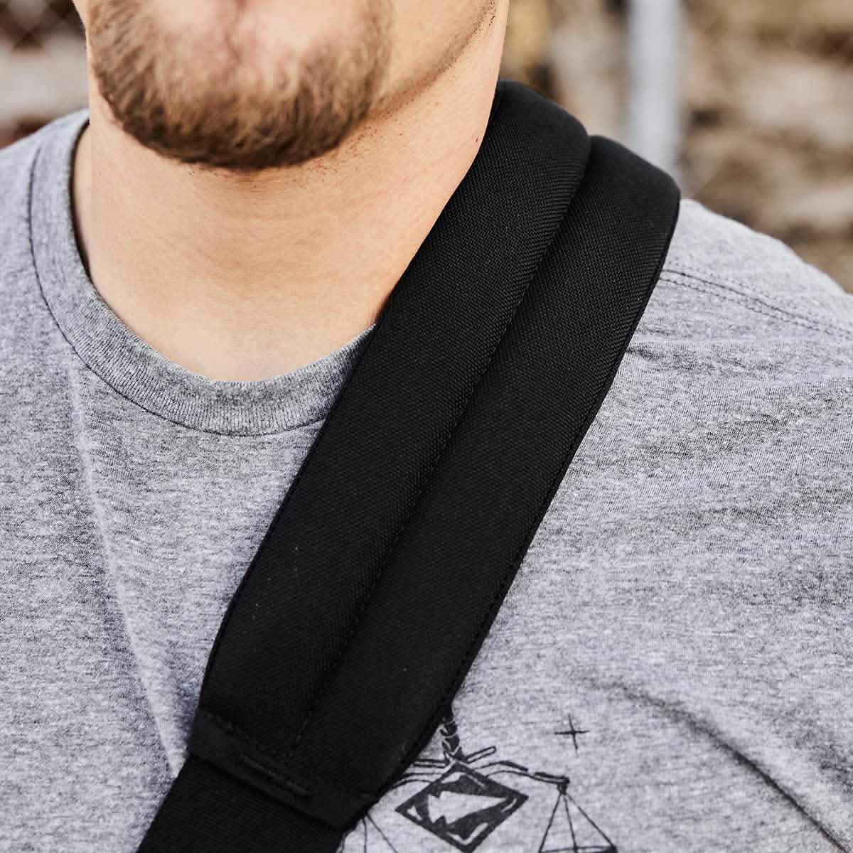 Close-up of a man wearing a gray GORUCK t-shirt and a padded black backpack strap over his shoulder