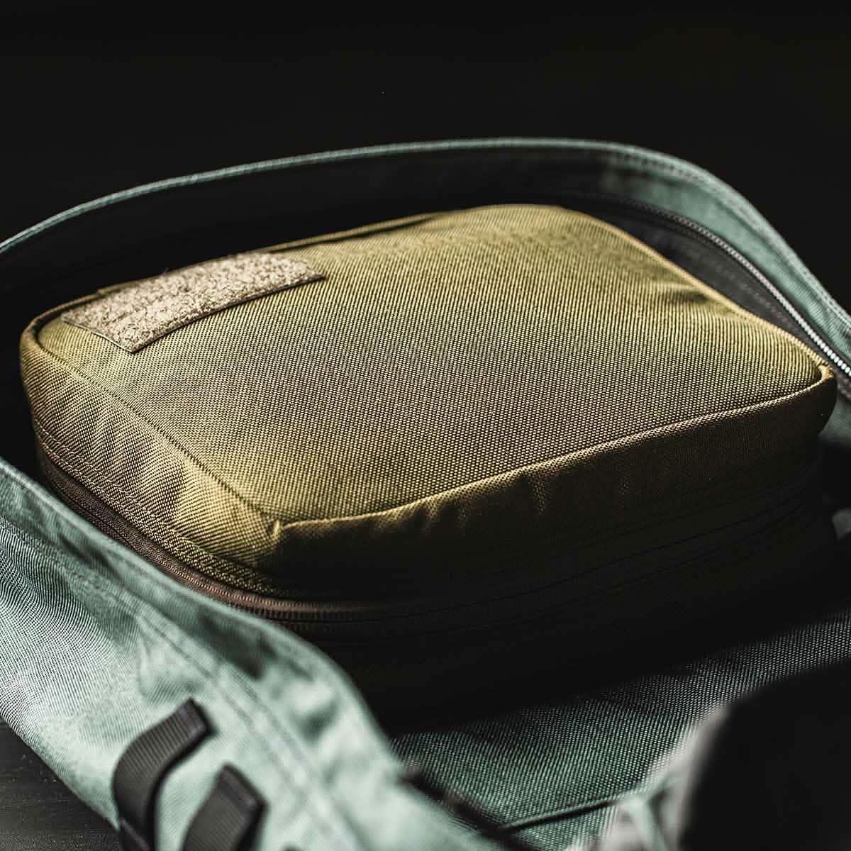 GORUCK tactical field pocket inside a partially open green rucksack bag on black background