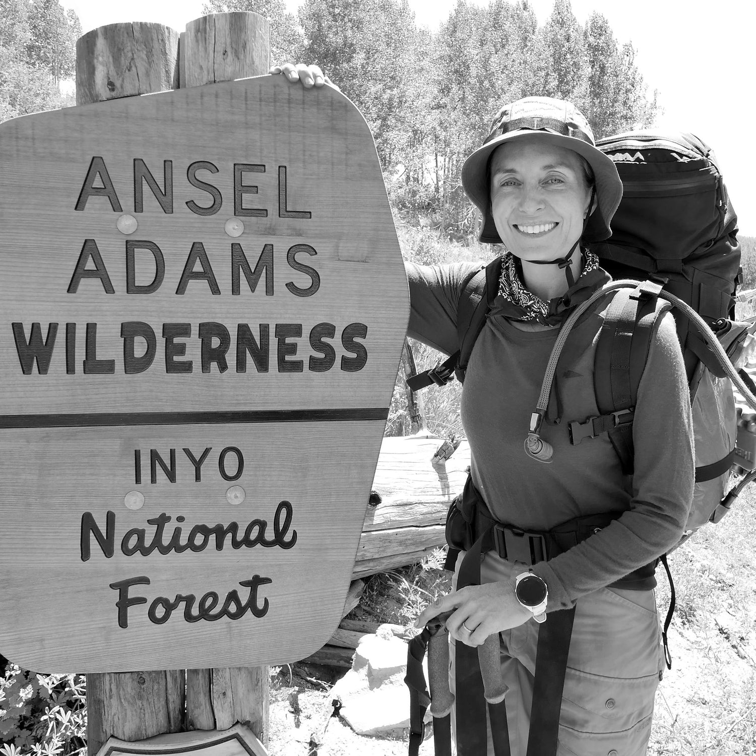 A smiling hiker with a GR MONSTER Bundle rucksack stands beside the Ansel Adams Wilderness sign in Inyo National Forest, outdoors.
