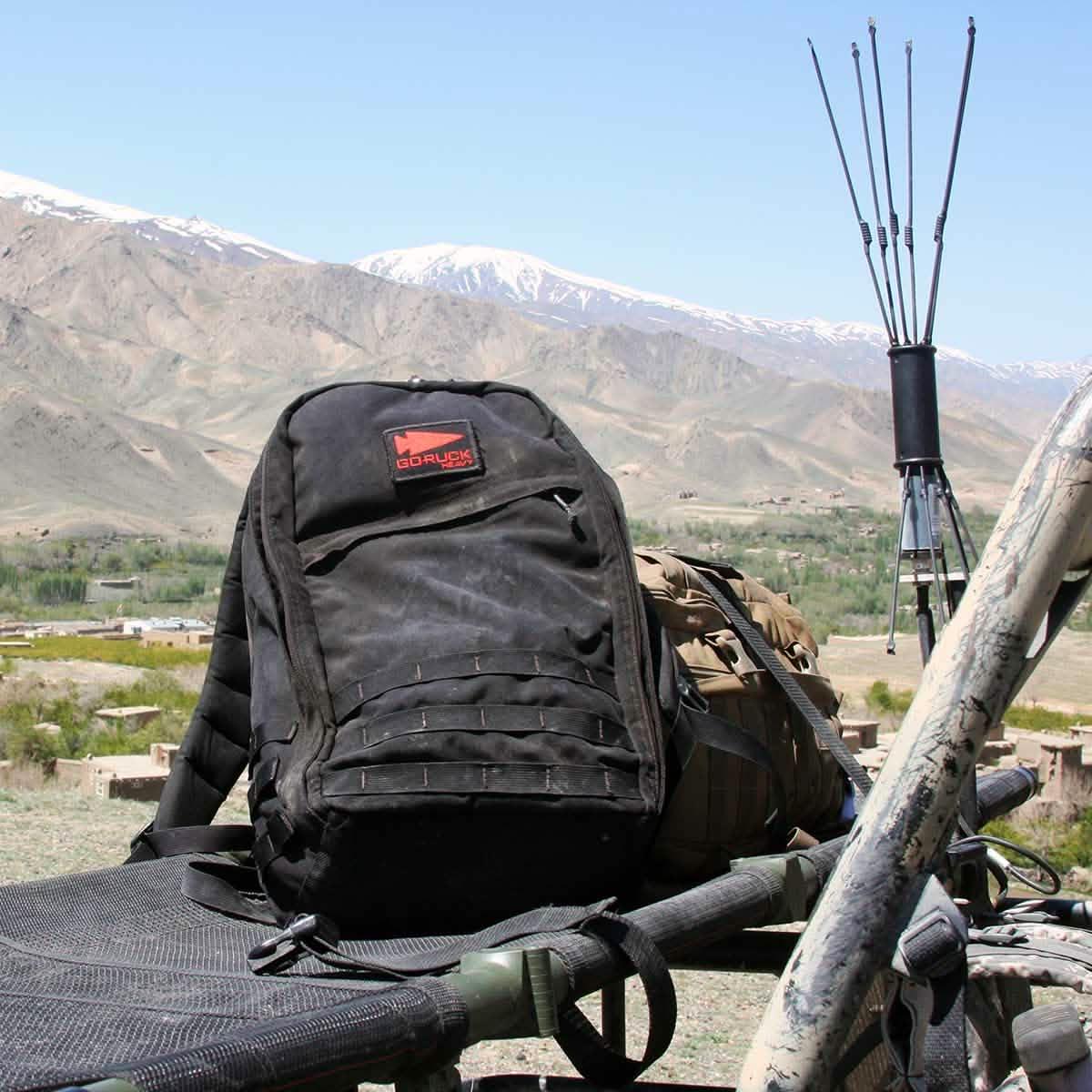 Black GORUCK backpack on military gear with mountains and clear sky in background