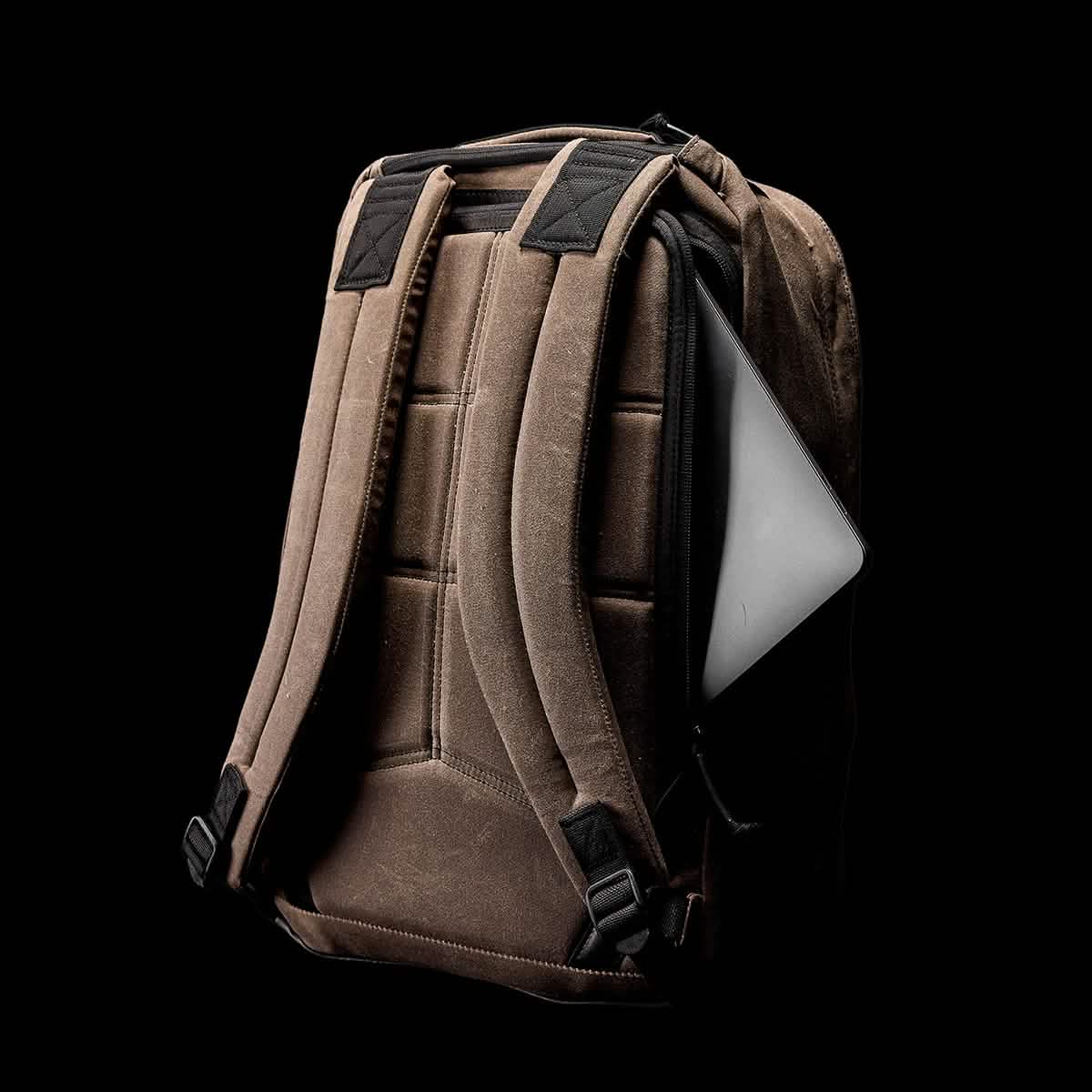 The GR1 USA - Heritage by GORUCK is a retro canvas rucksack showcased on a black background, featuring padded straps and a laptop partially visible in its compartment, highlighting the bag's functionality and storage capability.