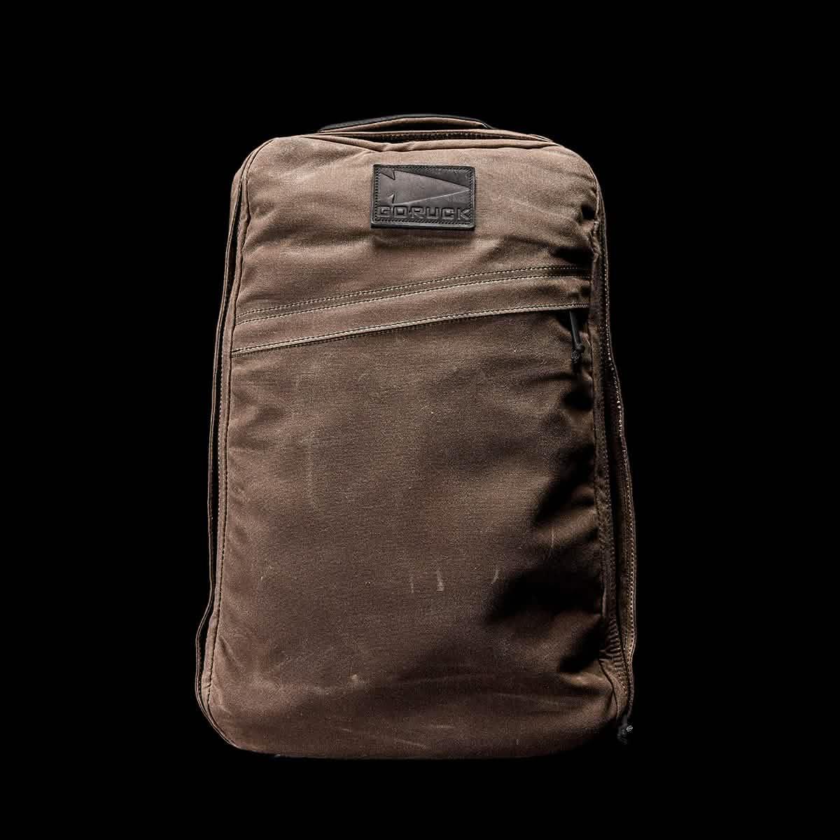 GORUCK Heritage Dark Oak rucksack, rugged brown tactical backpack with front zip pocket on black background
