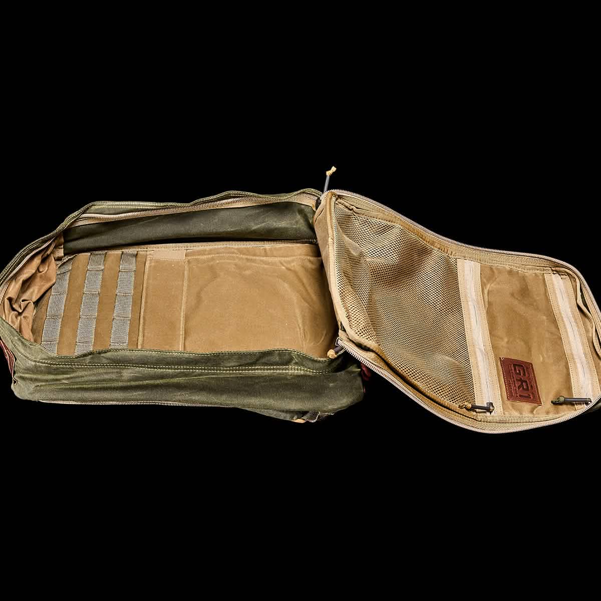 The GR1 USA - Heritage by GORUCK is an open green utility pouch crafted from waxed duck canvas, featuring multiple compartments and mesh pockets. The interior is equipped with elastic straps for organization and complemented by a brown leather patch with a rectangle symbol, echoing the design of the Heritage Backpack.