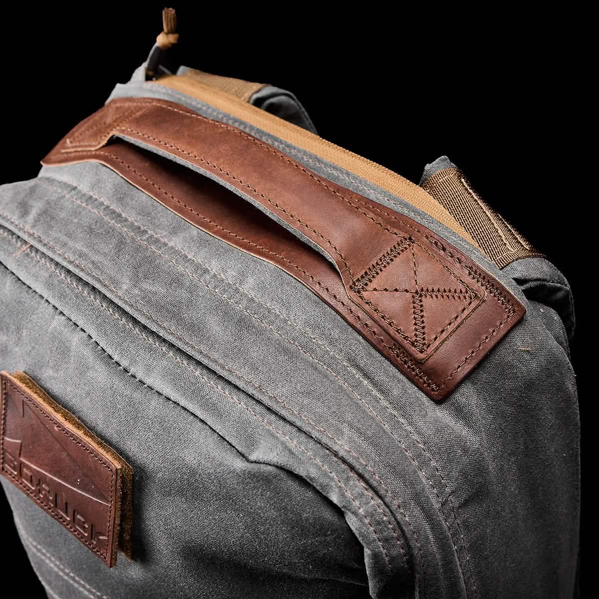 Close-up of GORUCK Heritage Slate backpack showing durable grey fabric and brown leather handle