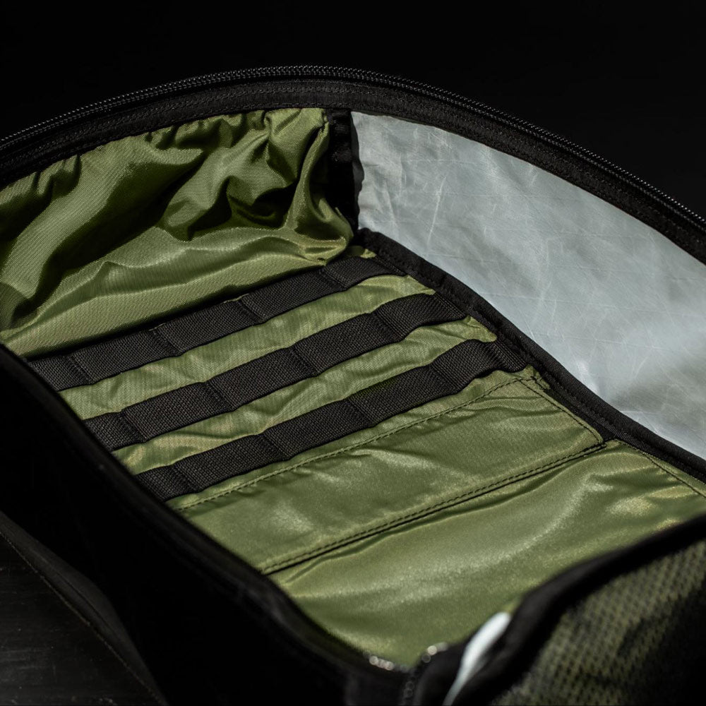 Open black bag with an olive green interior and multiple black elastic straps for organization.