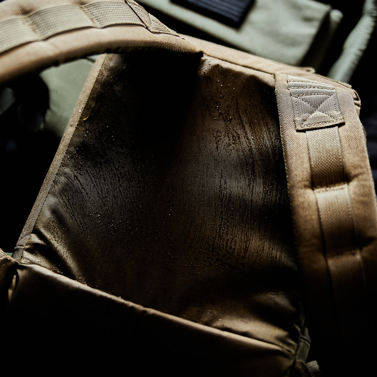 Close-up of a tan backpack strap and back panel with visible sweat marks and moisture stains.