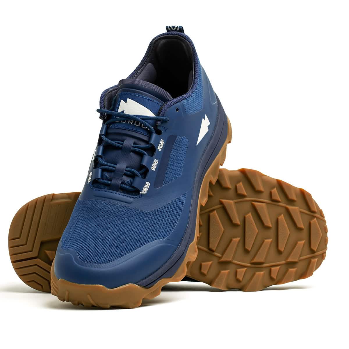 The Mackall trail running shoes by GORUCK in Legion Blue with gum-colored soles are ideal for Special Forces training. One shoe stands upright, highlighting the laces and logo, while the other is tilted to display the tread pattern. Created for outdoor pursuits, these shoes are the ultimate choice for trail adventures.