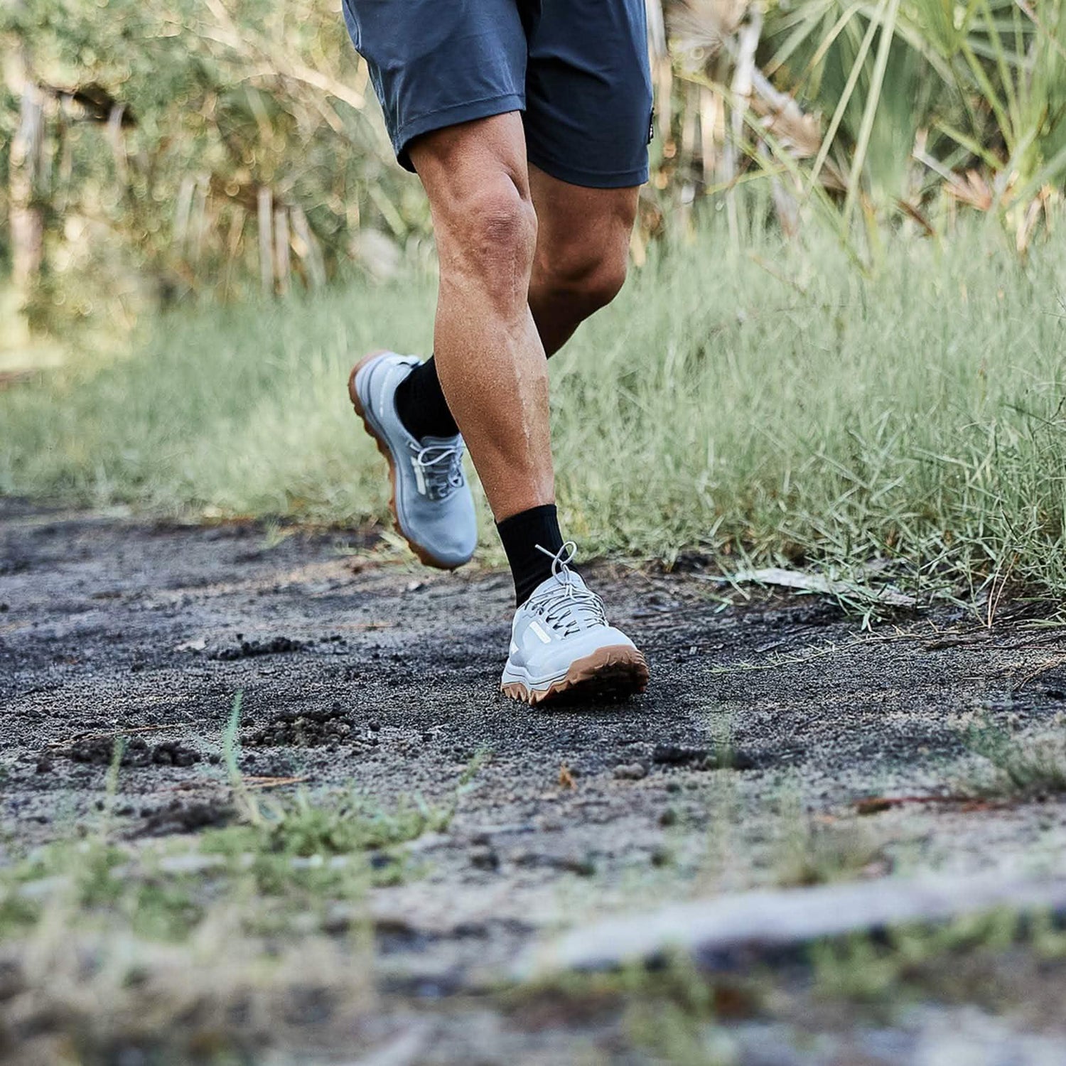 Man trail running in GORUCK rucking shoes and shorts on a dirt path outdoors