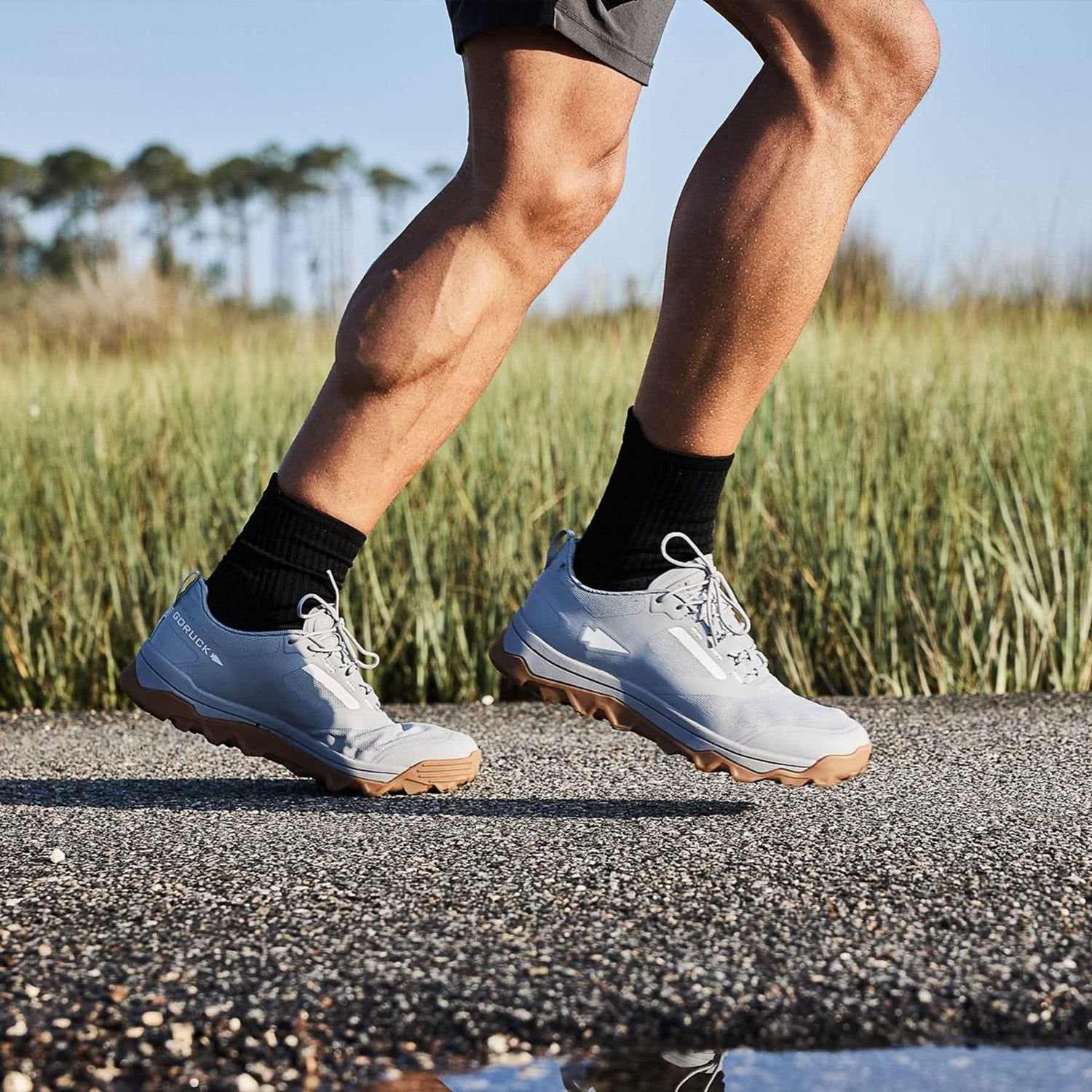 Close-up of a person running outdoors wearing GORUCK chiseled stone rucking shoes with black socks on a gravel path