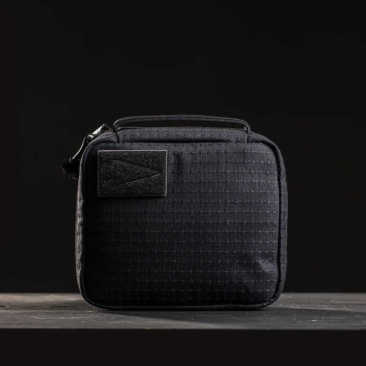 GORUCK compact black tactical pouch with grid texture and arrow patch on dark background