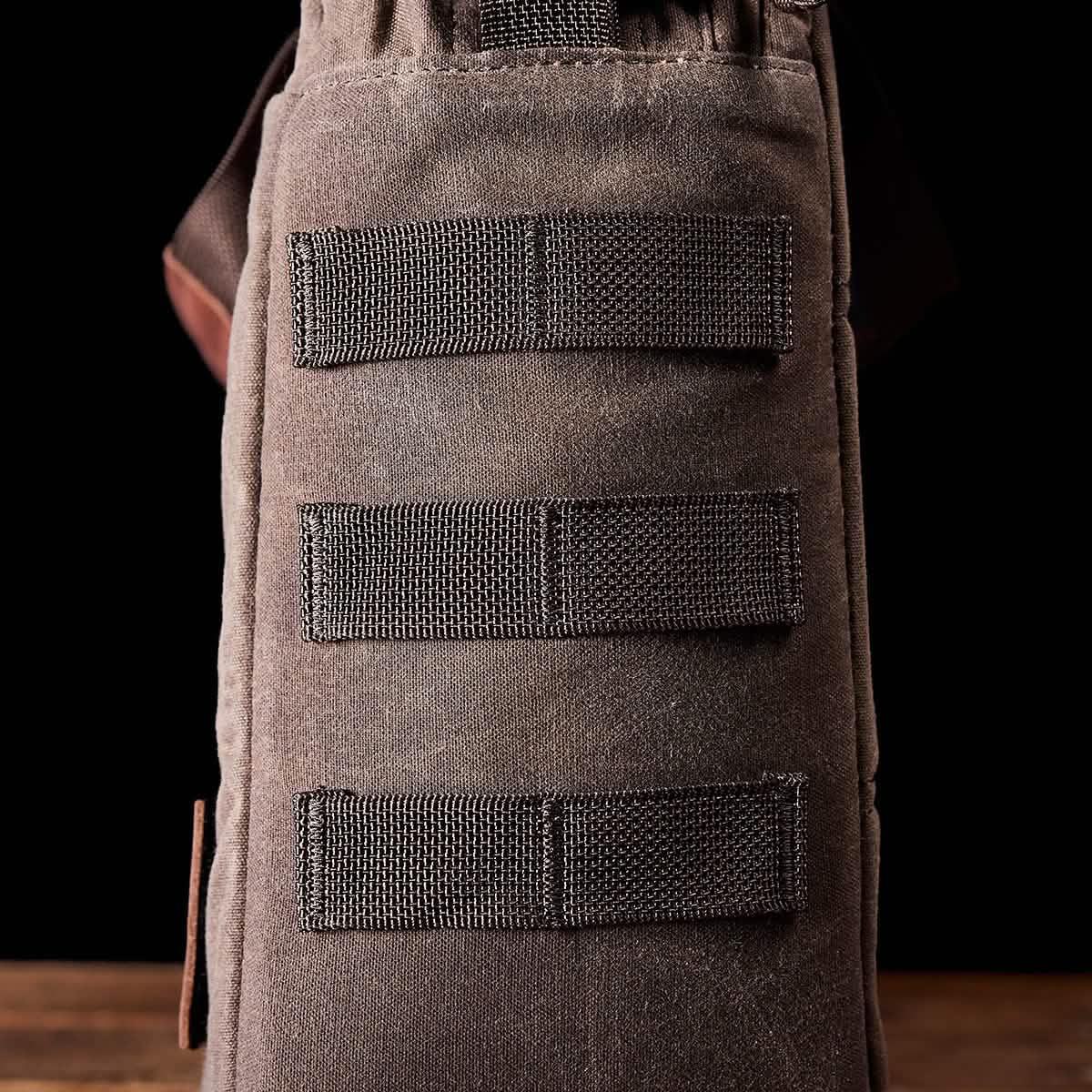 Close-up of durable brown GORUCK rucksack side with three stitched MOLLE-compatible webbing straps