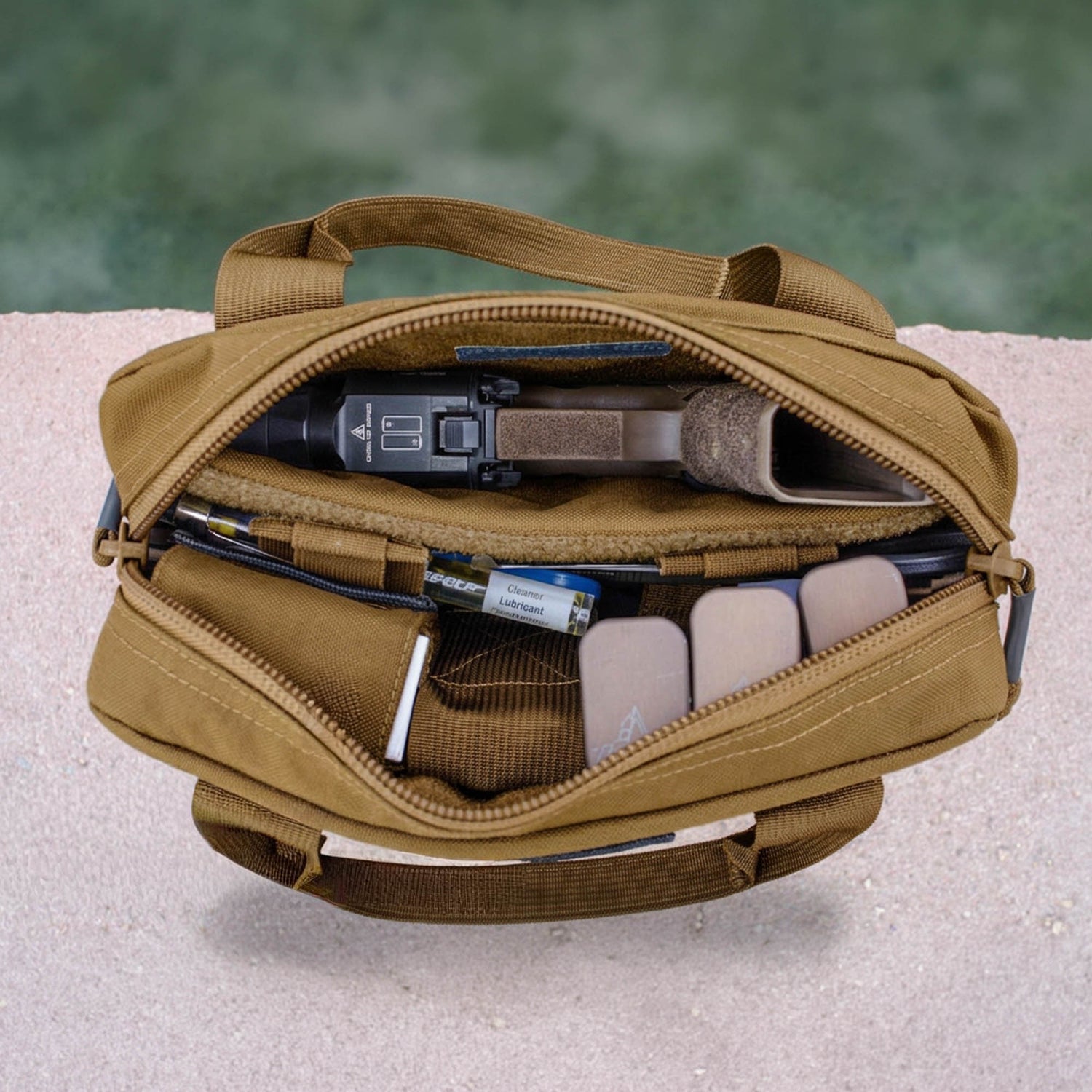 A brown Pistol Rug is open, displaying a handgun, magazines in a dedicated pouch, and other gear inside.