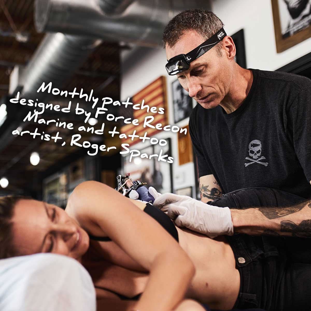 A tattoo artist captures dedication on a woman's side, reflecting the spirit of Roger Sparks' monthly patches and the grit of GORUCK Tribe's sandbag workouts in