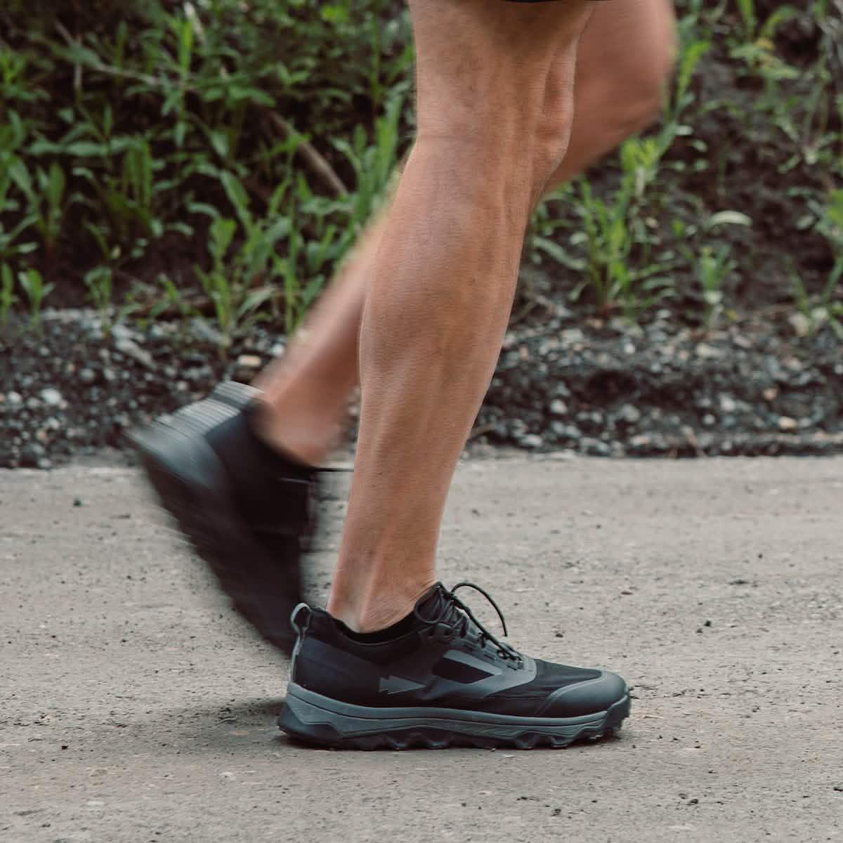 Person rucking outdoors wearing black GORUCK shoes on a dirt path