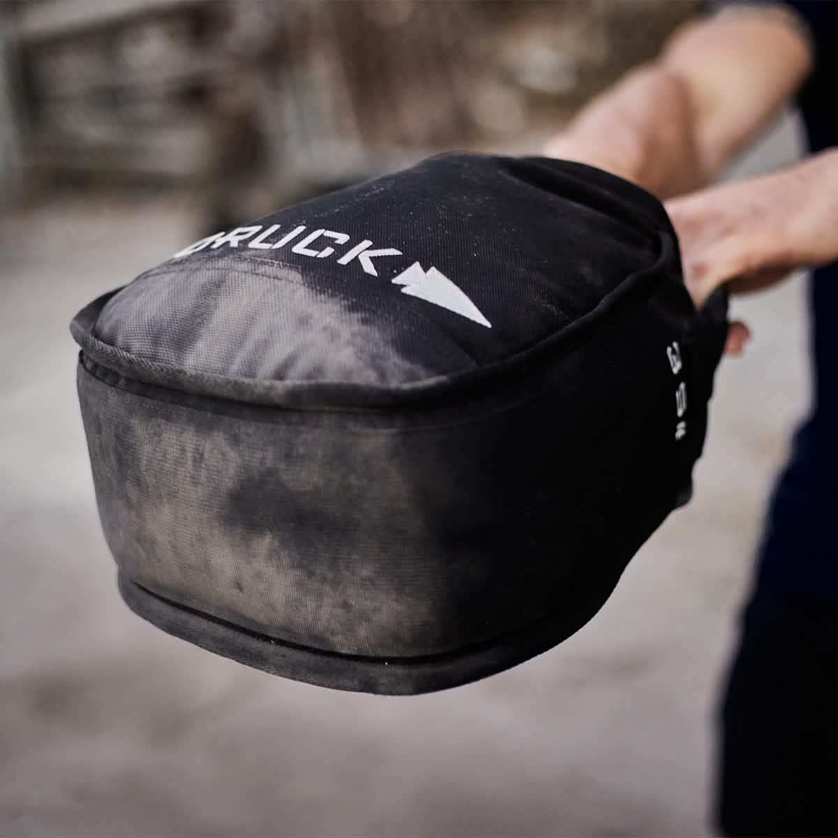 Person holding a dusty black GORUCK weighted rucksack gear bag up close