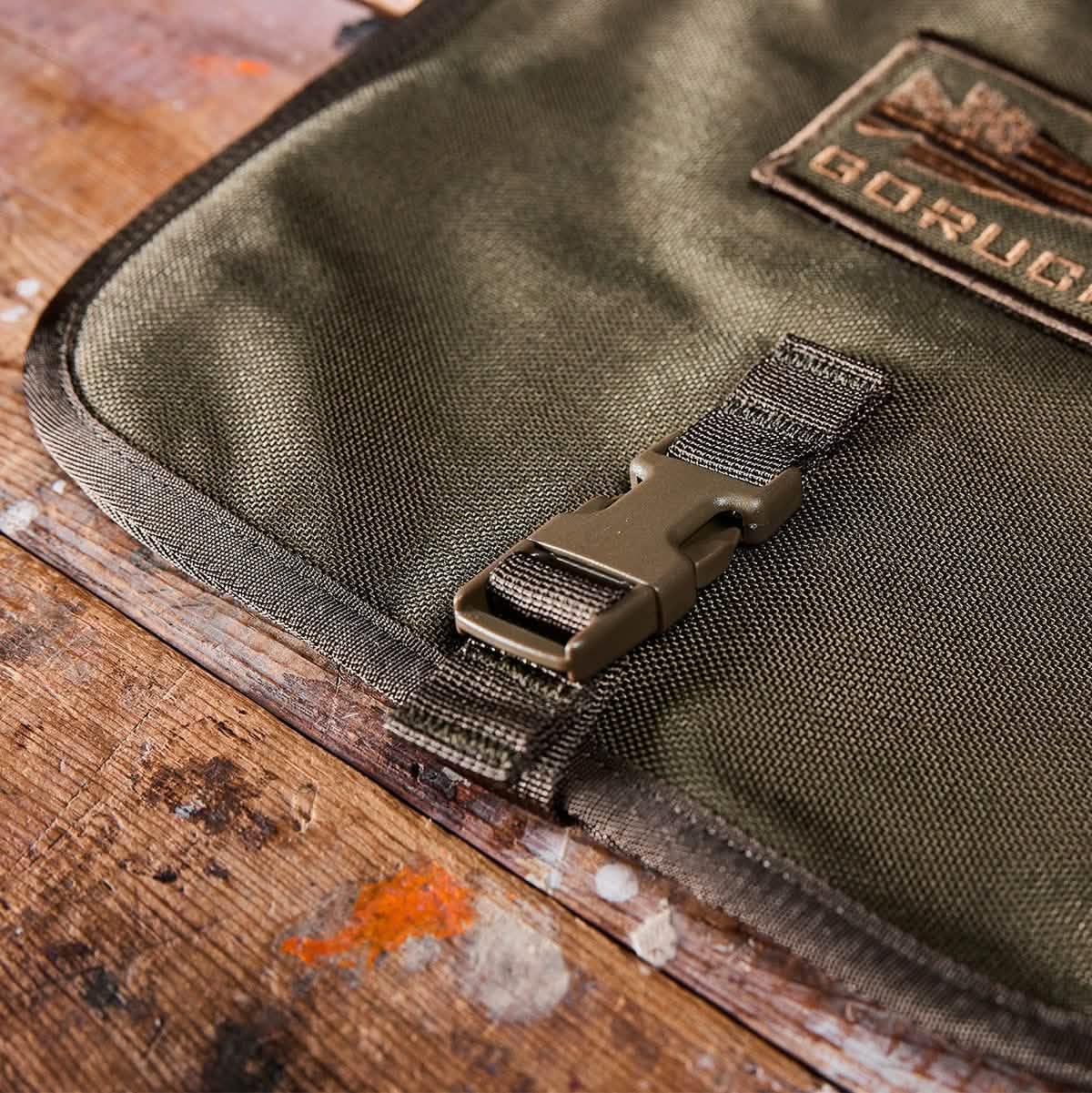 Close-up of GORUCK durable green tactical fabric with plastic buckle on wooden surface