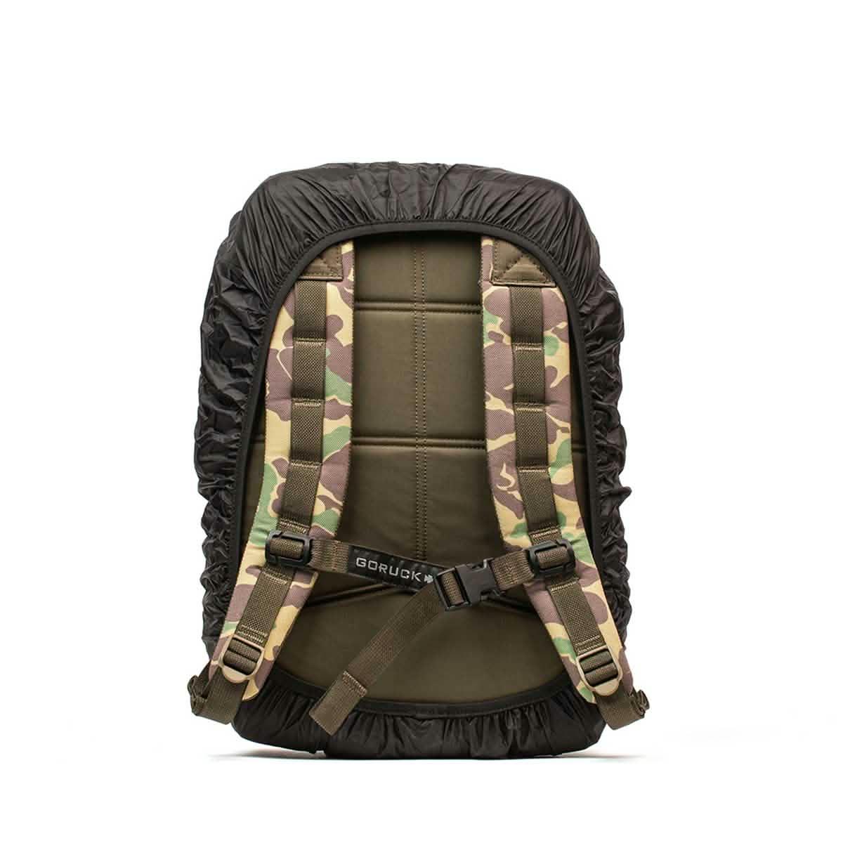 Back view of GORUCK camouflage padded backpack with black rain cover and adjustable straps