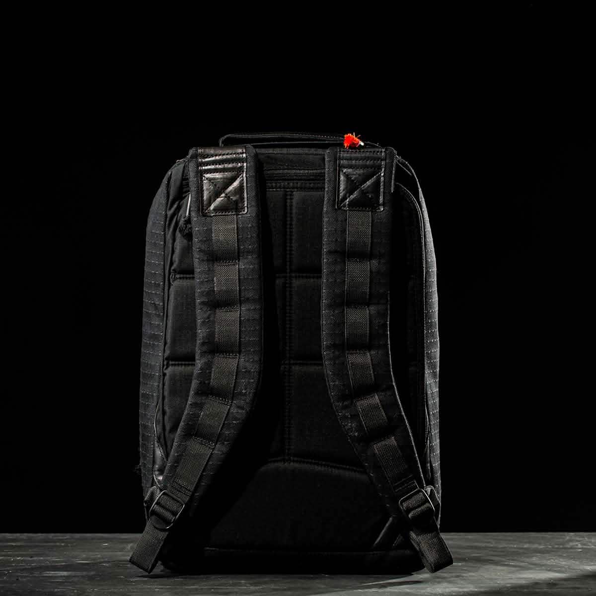 The GR1 USA x Carryology - GRXC2 Samurai, a black backpack with padded shoulder straps made from premium Japanese cotton fabric, is displayed from the back against a dark background.