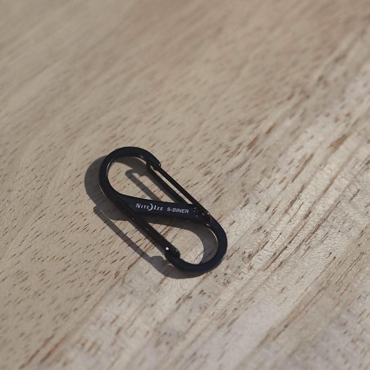 Black Nite Ize S-Biner carabiner on wood surface, GORUCK rucking gear accessory