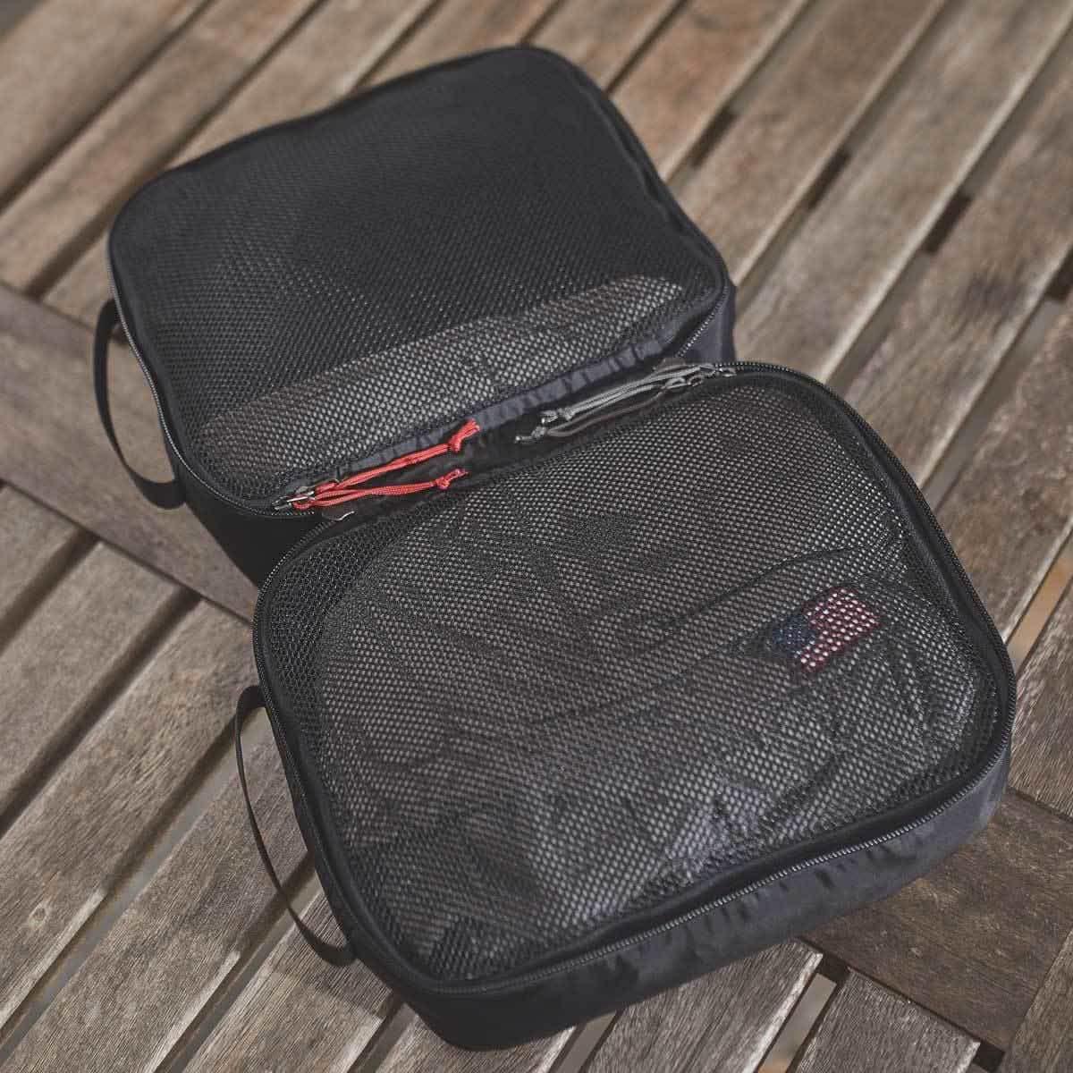 GORUCK black mesh packing cube on wood table, open to show spacious interior and zipper pulls