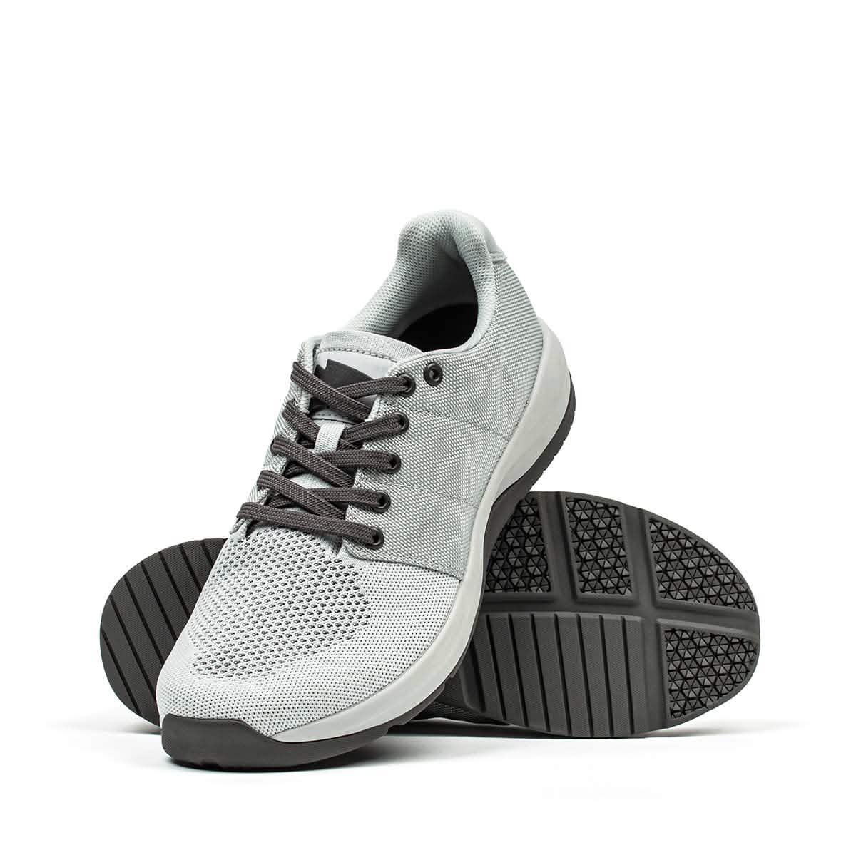 The Ballistic Trainers - Slick - Lunar Rock + Charcoal are versatile light gray athletic sneakers with black laces and textured soles, perfect for functional fitness workouts.