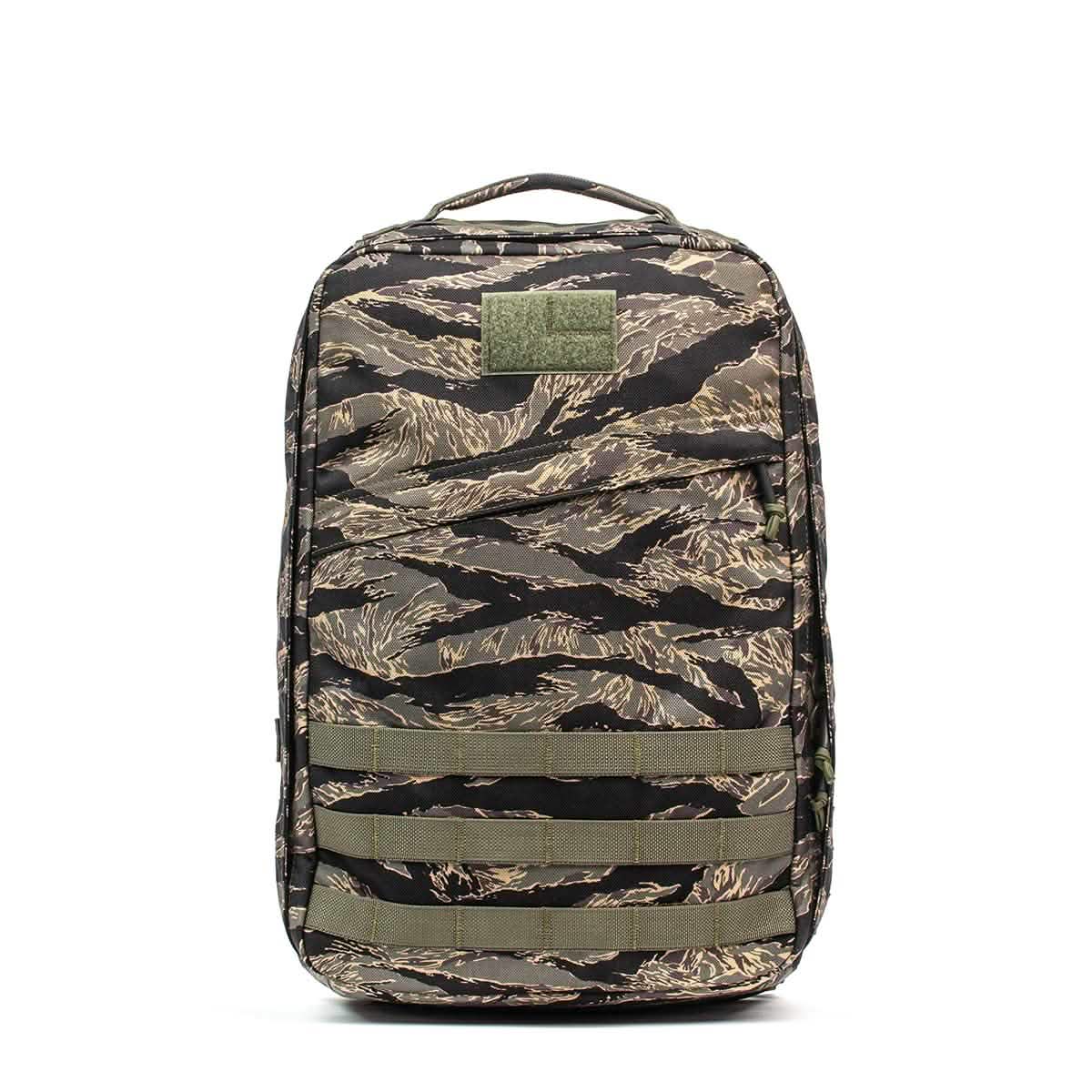 The GR1 - USA - Tiger Stripe backpack features a camouflage pattern, multiple straps, and a top handle, displayed against a white background.