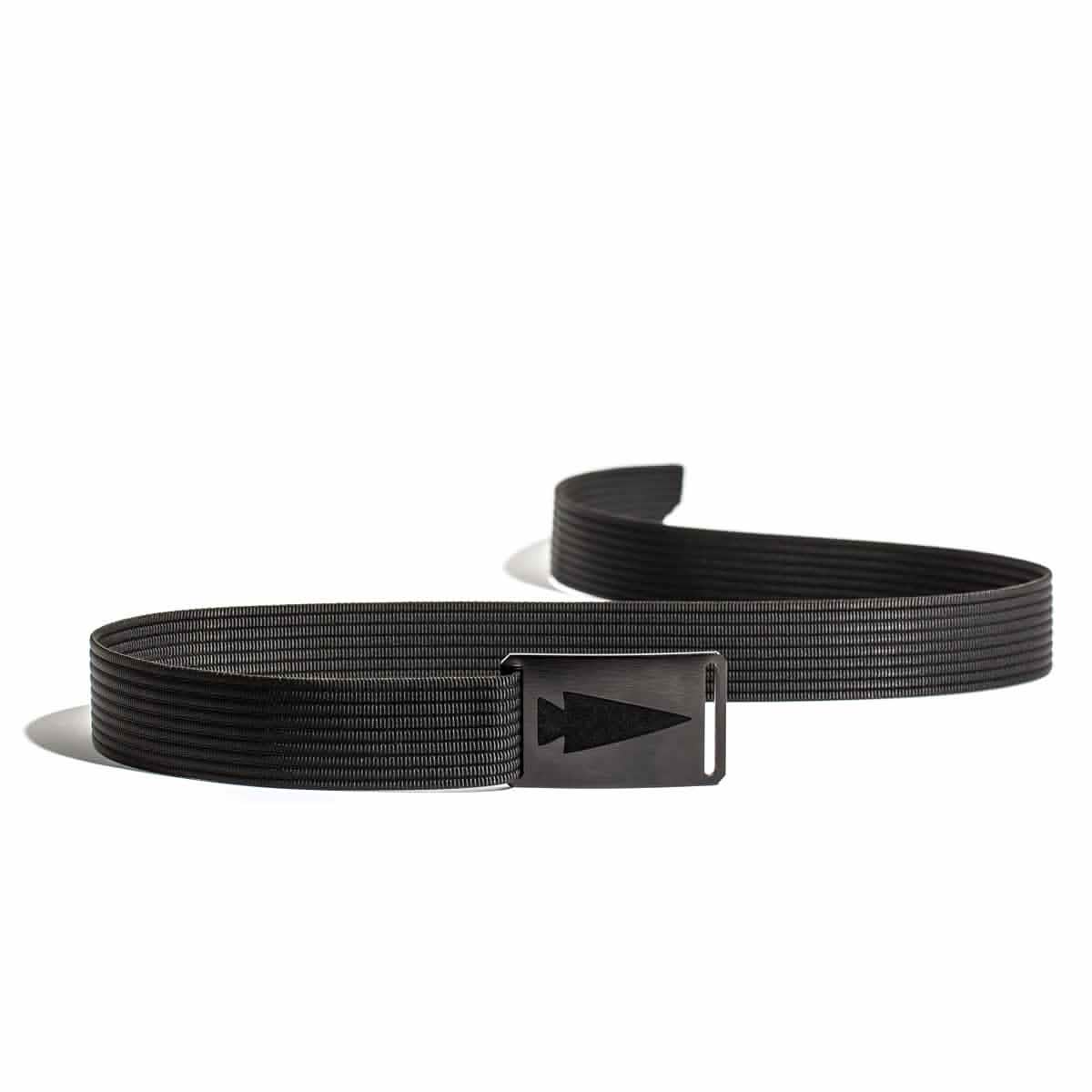 A black Spearhead Web Belt by Grip 6, showcasing a sleek arrow-shaped buckle and a no-slip locking mechanism, rests on a white background. The belt features a textured pattern and is slightly coiled, casting a subtle shadow while maintaining its low-profile design.