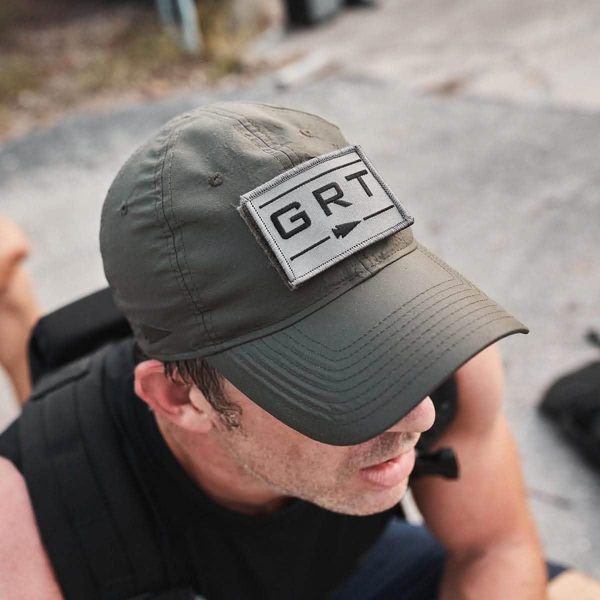 Man wearing olive green performance TAC rucking hat with GRT patch outdoors