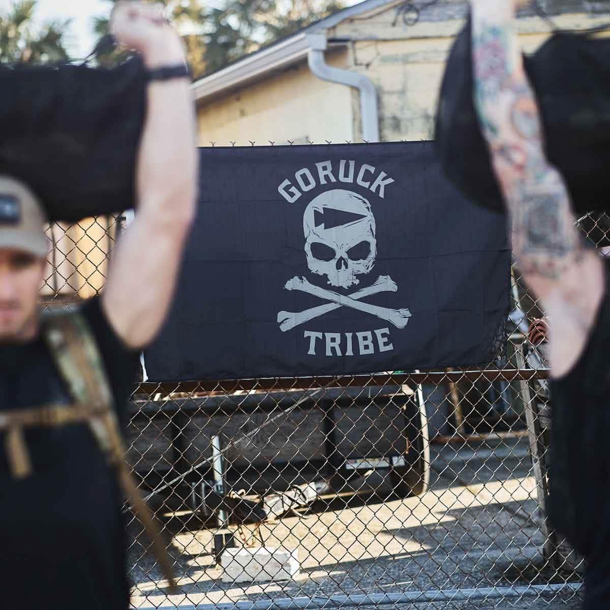 GORUCK Tribe flag with skull and crossbones design on a fence, outdoor rucking training scene