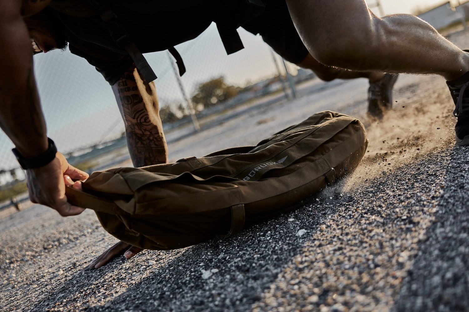 Man training outdoors with GORUCK sandbag, showing tough rucking gear in action