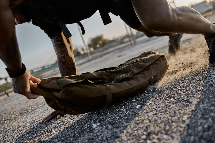 Man training outdoors with GORUCK sandbag, showing tough rucking gear in action