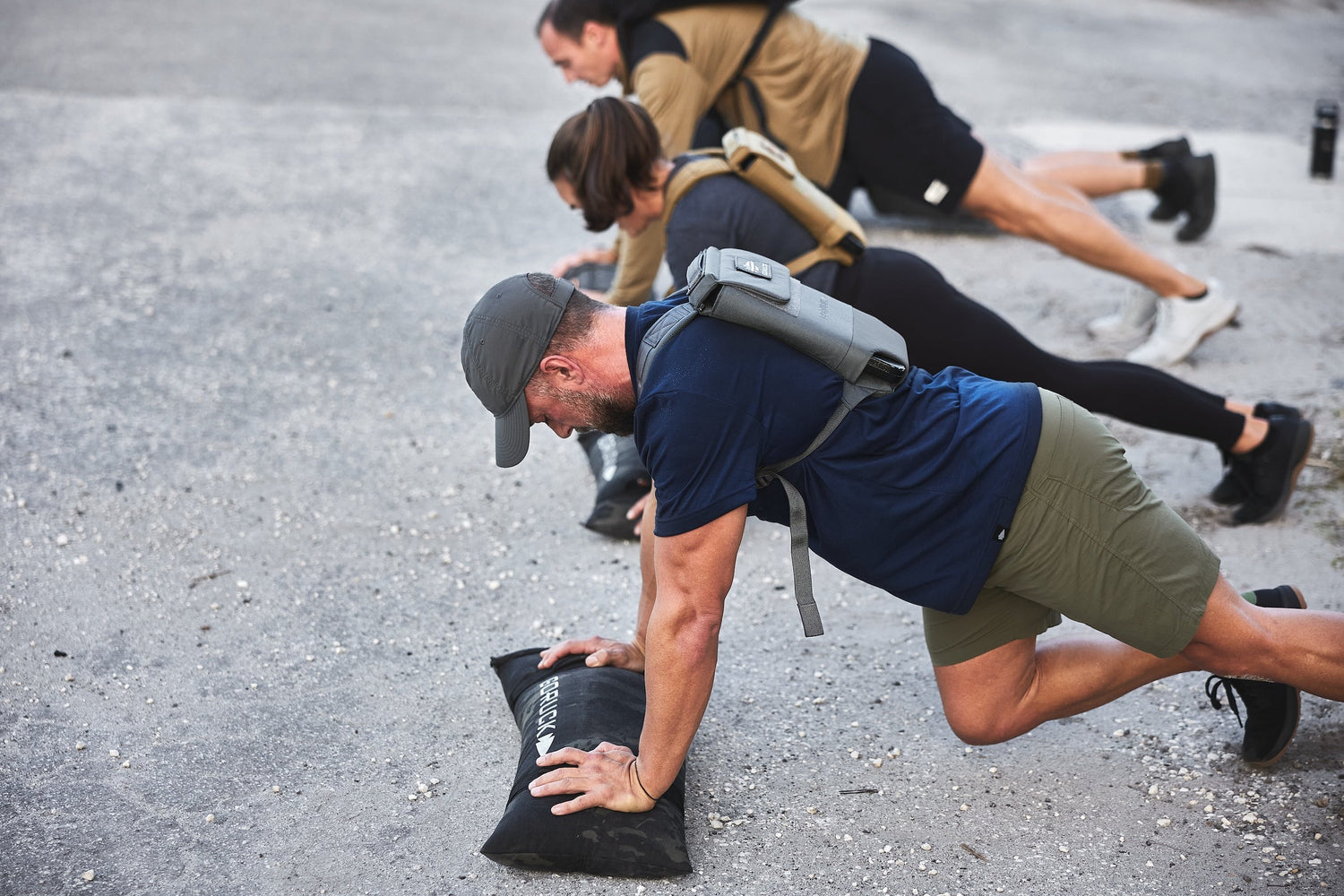 People wearing GORUCK gear doing outdoor push-up workout on rough pavement
