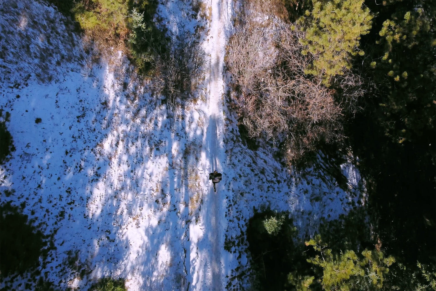 Person rucking on snowy forest trail with GORUCK backpack, aerial winter outdoor scene