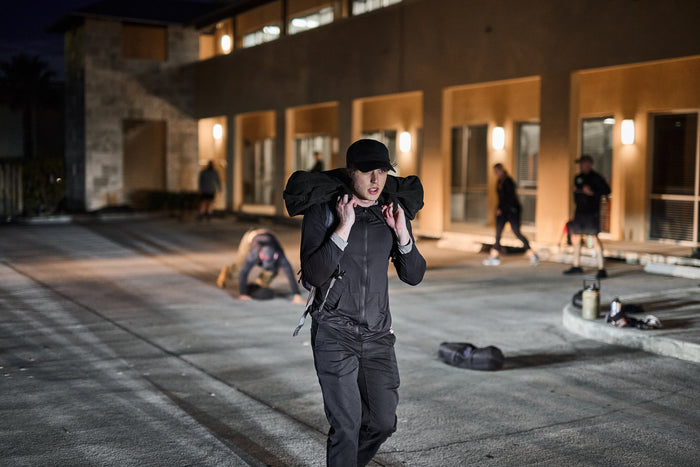 Person rucking with weighted sandbag at night during GORUCK club outdoor fitness event