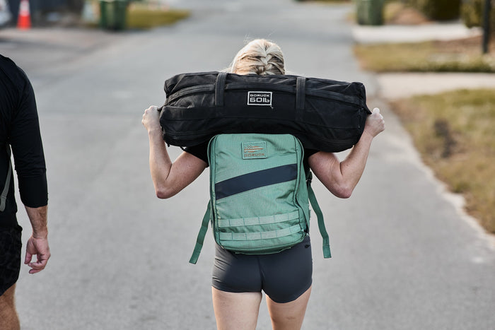 Person rucking with a GORUCK backpack and sandbag on a suburban street
