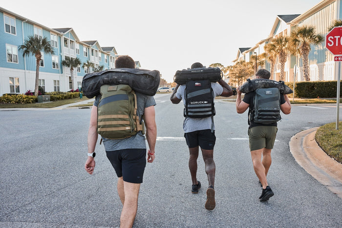 Three men rucking with GORUCK backpacks and sandbags on a suburban street