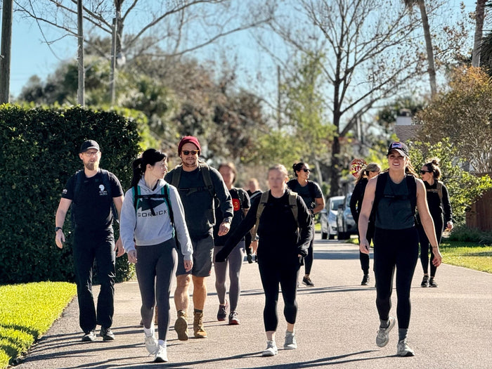 Group of people rucking outdoors with GORUCK gear on a sunny day, community fitness event