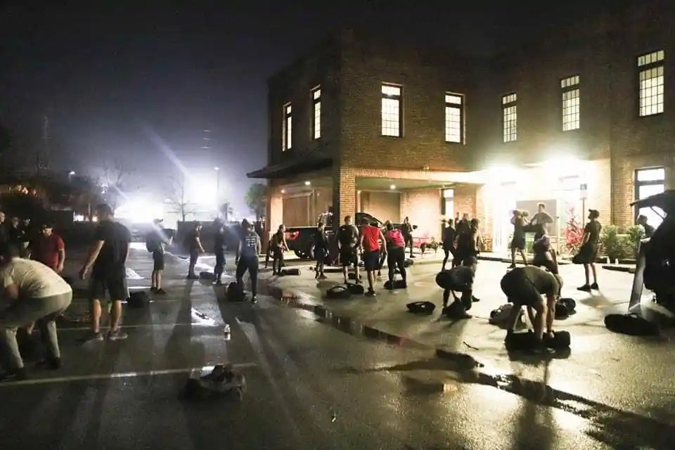 Group rucking event at night outside brick building, GORUCK gear, community workout