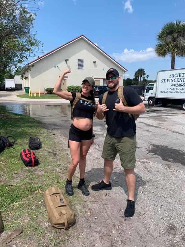 Two people posing outdoors with GORUCK rucksacks, ready for a rucking event
