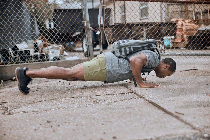 Man doing outdoor push-ups wearing GORUCK backpack and athletic gear