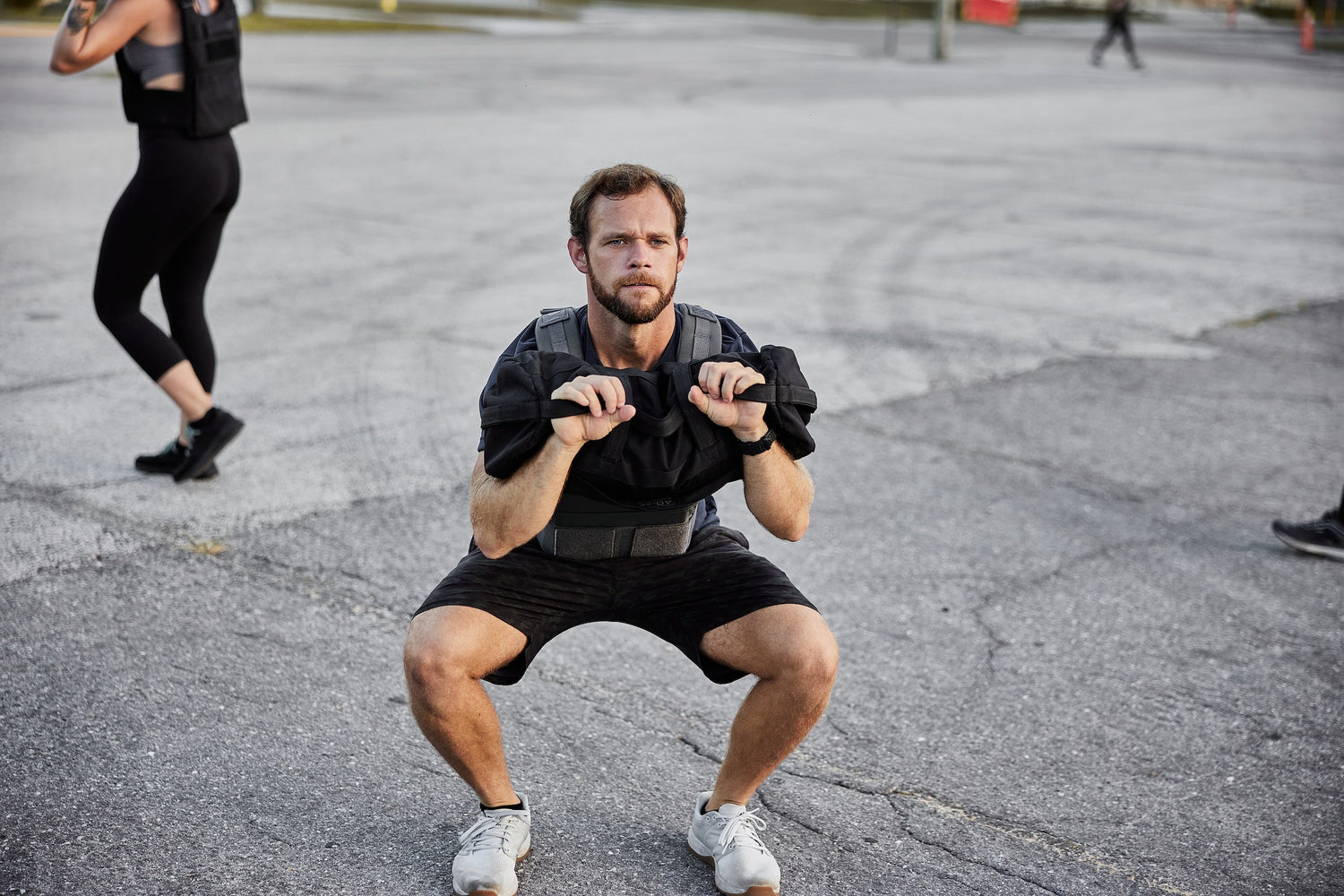 Man performing outdoor squat wearing a ruck plate carrier, GORUCK fitness training gear