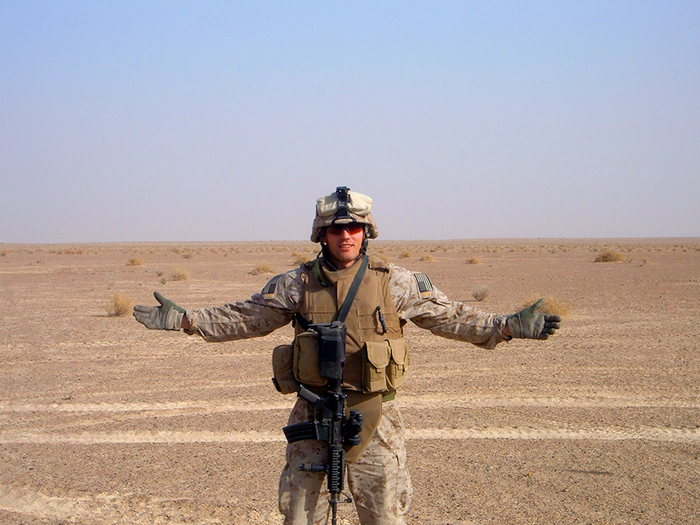 GORUCK military member in tactical gear standing in a desert landscape with arms open