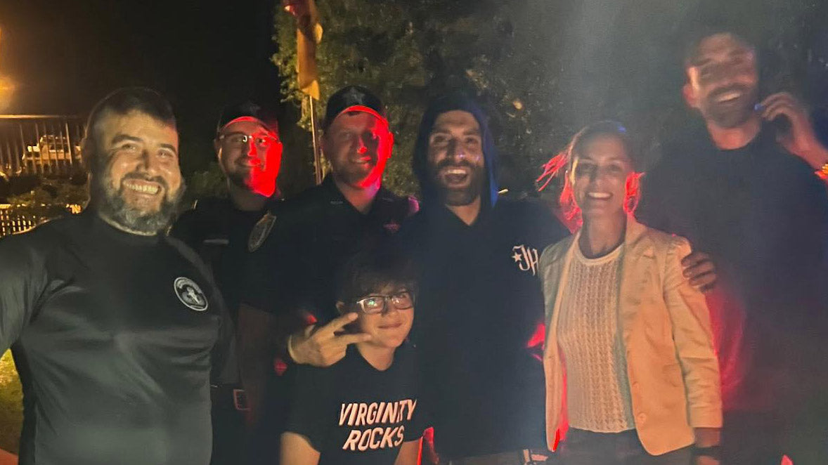 Group of seven people smiling outdoors at night, featuring men and a woman with casual clothing and friendly expressions