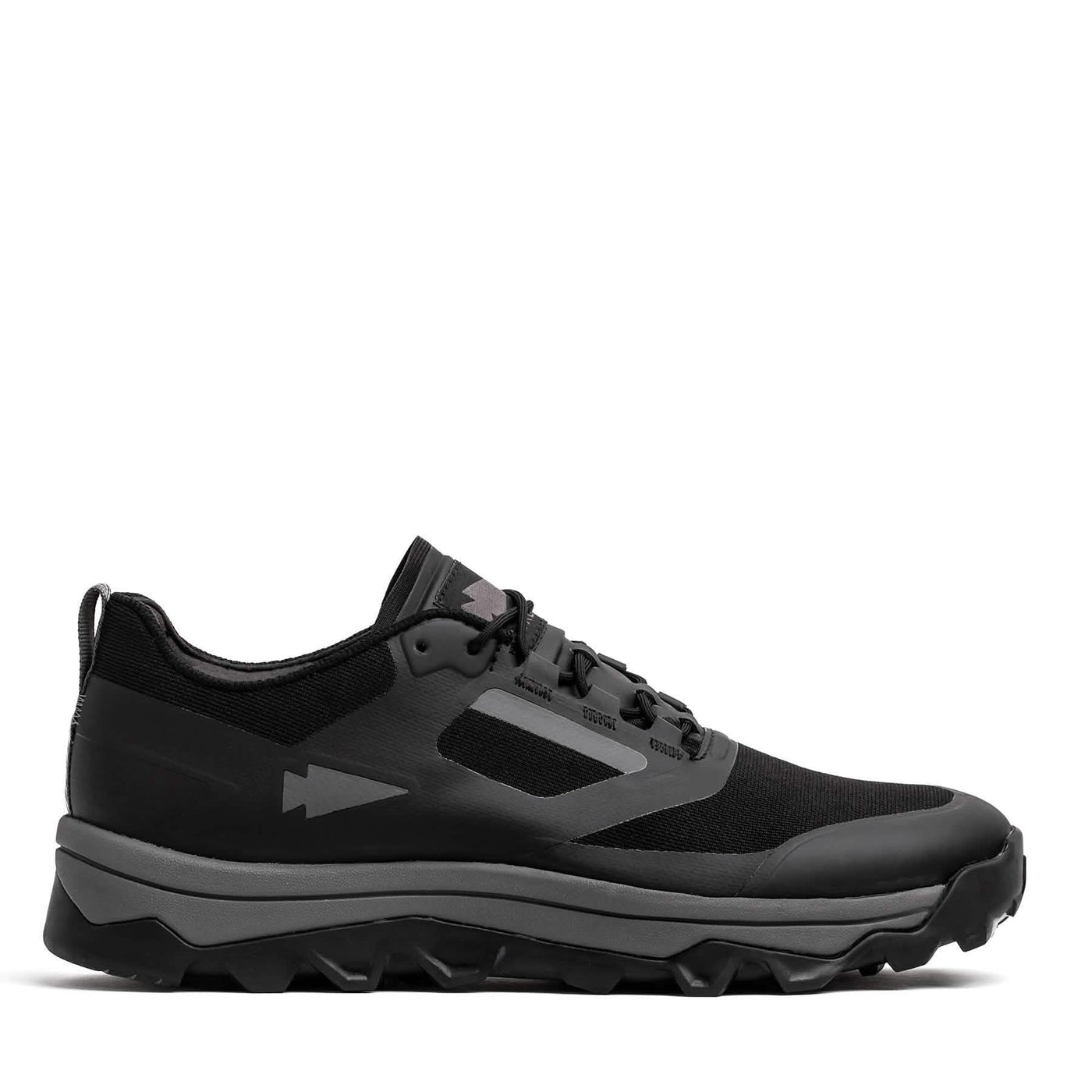 The GORUCK Mackall in Black and Forged Iron is a trail shoe ideal for Special Forces training, featuring a rugged sole crafted from mesh and synthetic materials. It boasts a low-profile design with a lace-up closure and displays a subtle arrow symbol on the side.