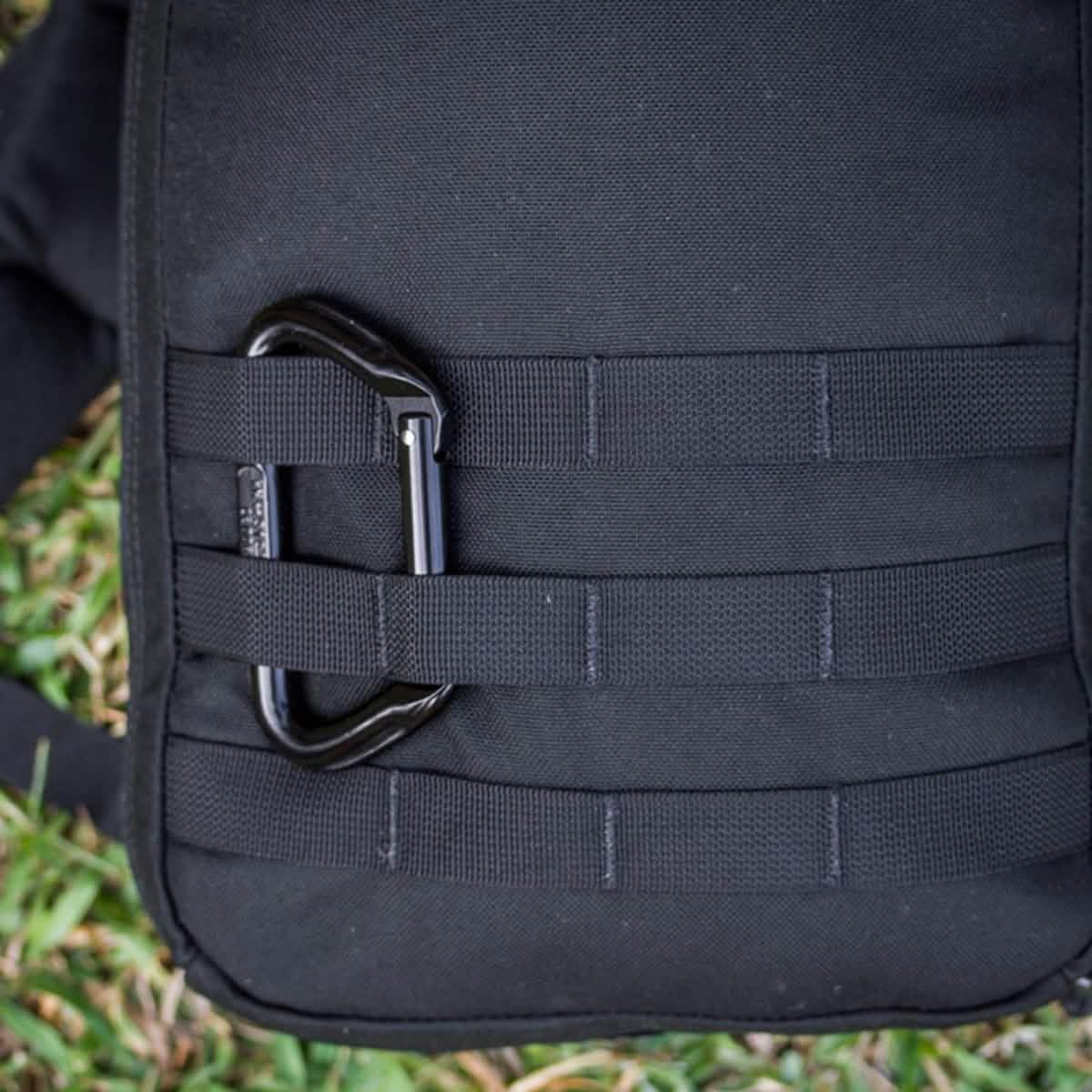 GORUCK rucksack with black carabiner clipped to MOLLE webbing on grass