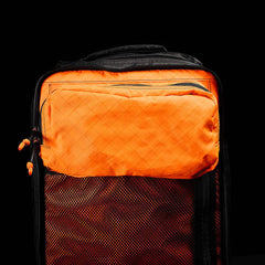 The GR2 USA x Carryology - Ultra Black is an orange and black backpack made with Challenge Sailcloth UHMWPE fabric and features a zippered front pocket, shown against a black background.