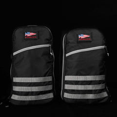 Two black GORUCK rucksacks with American flag logo patches and gray horizontal straps on black background