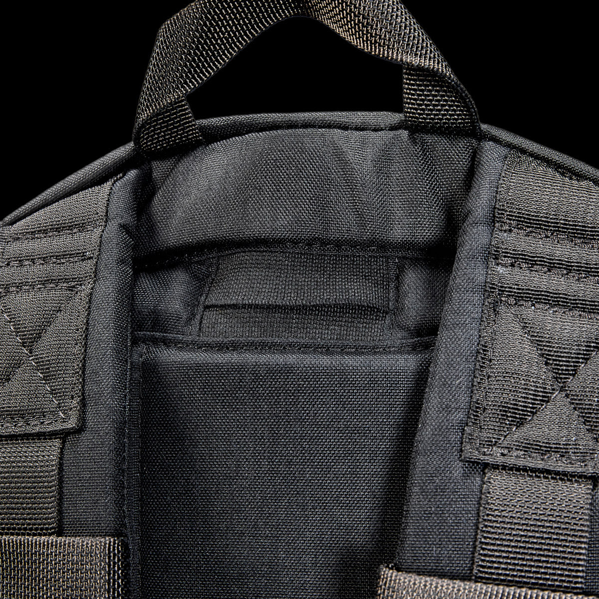 Close-up of the top part of the Bullet Ruck USA Throwback, a black tactical daypack featuring padded straps, a carrying handle, and durable CORDURA construction.